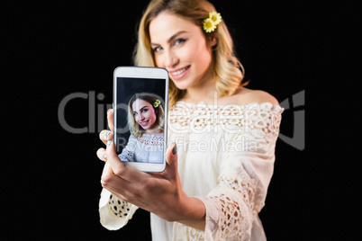 Beautiful woman clicking photo from mobile phone against black background