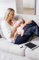 Mother feeding her baby with milk bottle in living room
