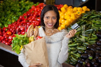 Woman holding credit card and grocery bag