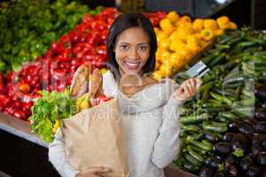 Woman holding credit card and grocery bag