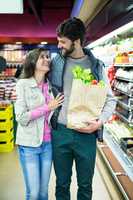 Smiling couple shopping for vegetables in organic section