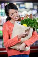 Woman using mobile phone while holding groceries