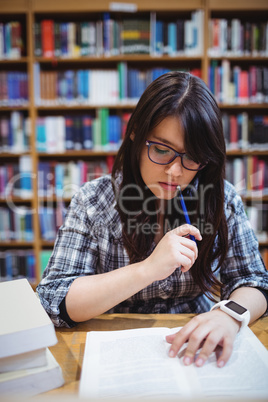 Female student looking at notes in library