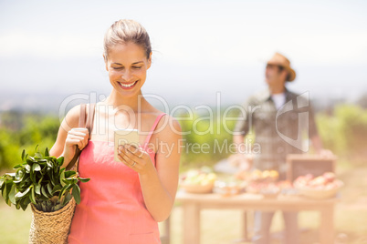 Female customer using mobile phone in front of vegetable stall