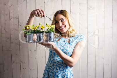 Woman holding a basket of plant pots against texture background