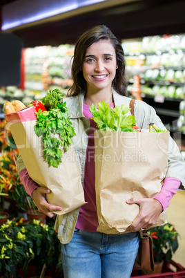 Portrait of smiling woman holding a grocery bag in organic section