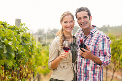 Portrait of happy couple holding glass and a bottle of wine