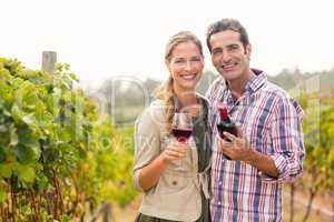 Portrait of happy couple holding glass and a bottle of wine
