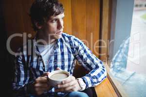 Student looking through window while having coffee