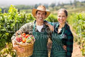 Portrait of happy farmer couple holding a basket of vegetables