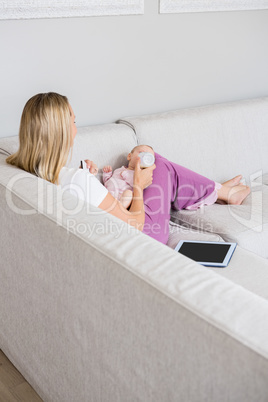 Mother feeding baby with milk bottle in living room