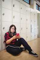 Female student using mobile phone in locker room