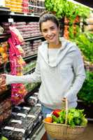 Smiling woman shopping in grocery section of supermarket