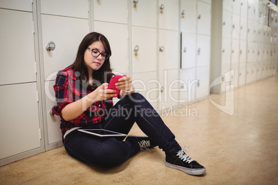 Female student using mobile phone in locker room