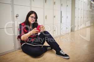 Female student using mobile phone in locker room