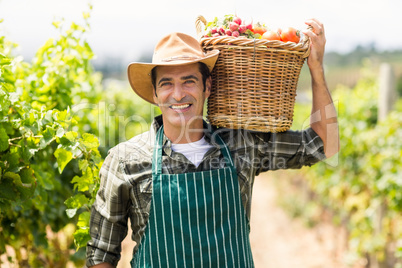 Portrait of happy farmer carrying a basket of vegetables