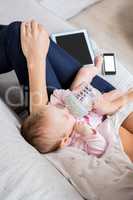 Mother feeding her baby with milk bottle in living room