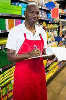 Smiling male staff writing on notepad in super market