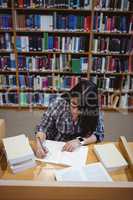 Female student writing notes in library