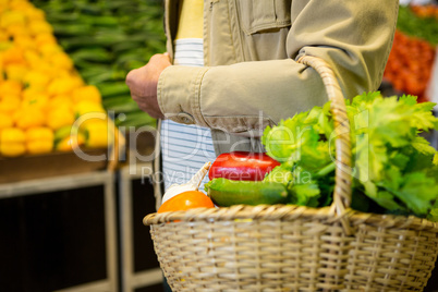 Man holding a basket of vegetables in super market
