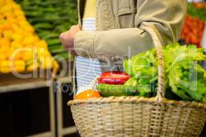 Man holding a basket of vegetables in super market