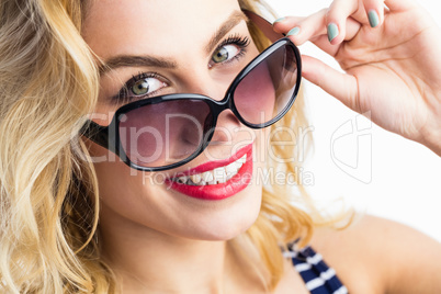 Portrait of beautiful woman posing with sunglasses against white background