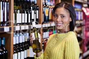 Woman holding wine bottle in grocery section