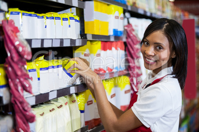 Female staff arranging goods in grocery section