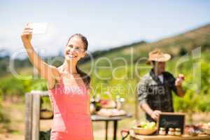 Female customer taking a selfie in front of vegetable stall