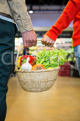 Couple holding a basket of vegetables in super market