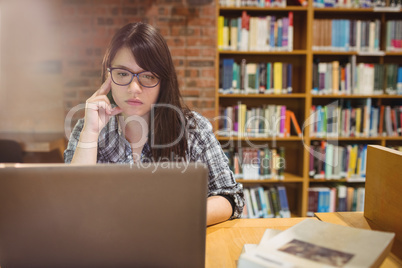 Thoughtful female student using laptop