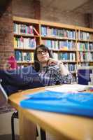 Female student sitting in library with mobile phone