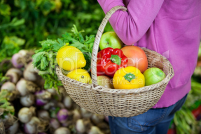 Woman holding fruits and vegetables in basket