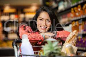 Happy woman leaning on shopping cart
