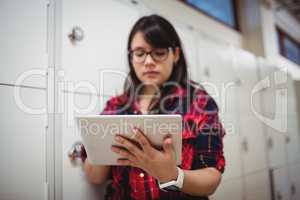 Female student using digital tablet in locker room