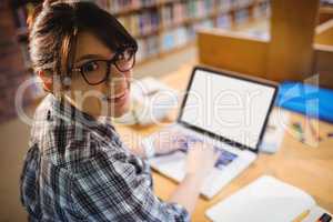 Smiling Female student using laptop in library