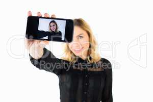 Smiling woman clicking photo from mobile phone against white background