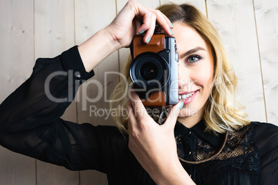 Smiling woman clicking photo from camera against texture background