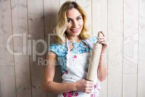 Woman in apron holding a rolling pin against texture background