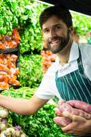 Male staff arranging vegetables in organic section