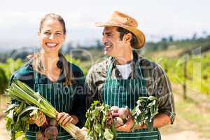 Happy farmer couple holding leafy vegetables