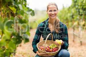 Happy female vintner holding a basket of grapes