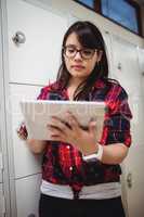 Female student using digital tablet in locker room