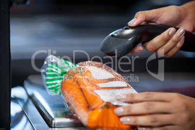 Woman scanning goods at checkout counter