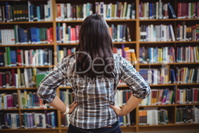 Rear view of female student looking at books in the shelf