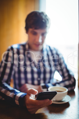 Student using mobile phone while having coffee