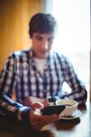 Student using mobile phone while having coffee