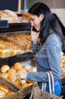 Woman talking on mobile phone at bread counter