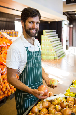 Male staff arranging fruits in organic section of supermarket