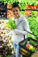 Smiling woman buying vegetables in organic shop